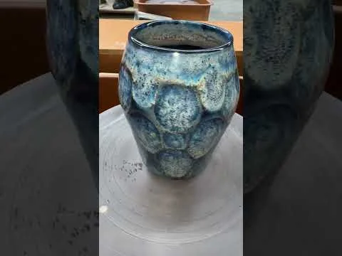 A blue-green glazed ceramic vessel with a rounded, textured surface.